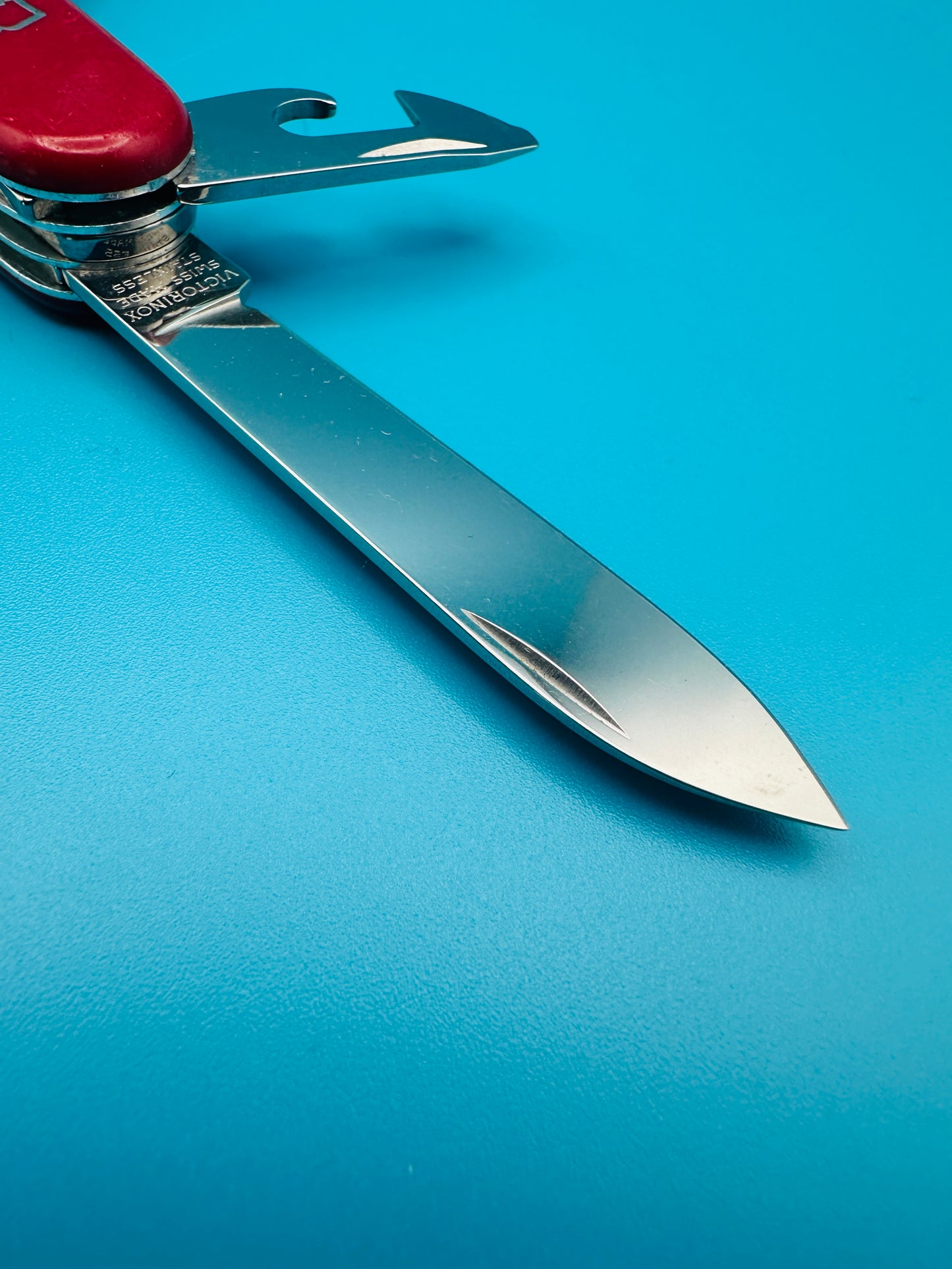 Side view of large blade of Super Tinker knife on blue background