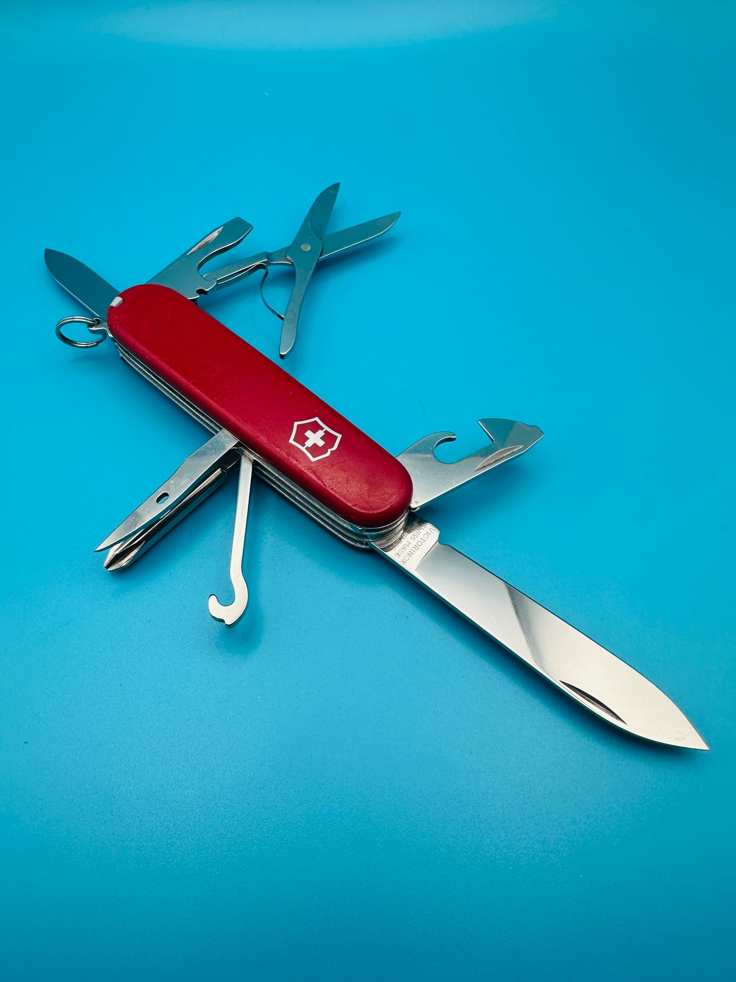 Used Victorinox Super Tinker Swiss Army knife with tools open on blue background