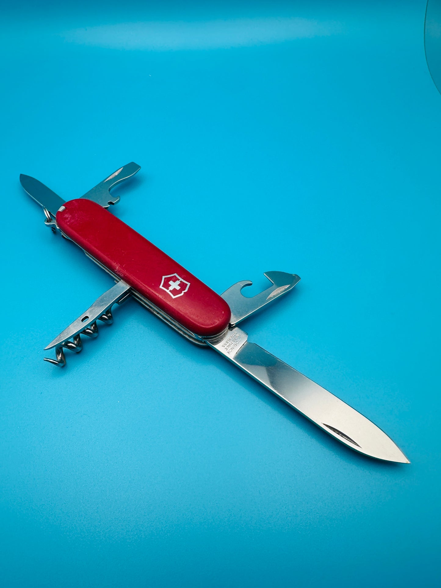 Victorinox Spartan Swiss Army knife with blade and tools open on blue background