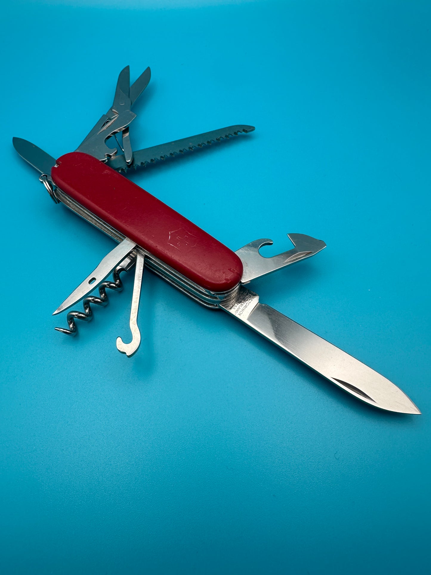Victorinox Huntsman Swiss Army knife with large blade and tools open on a blue background