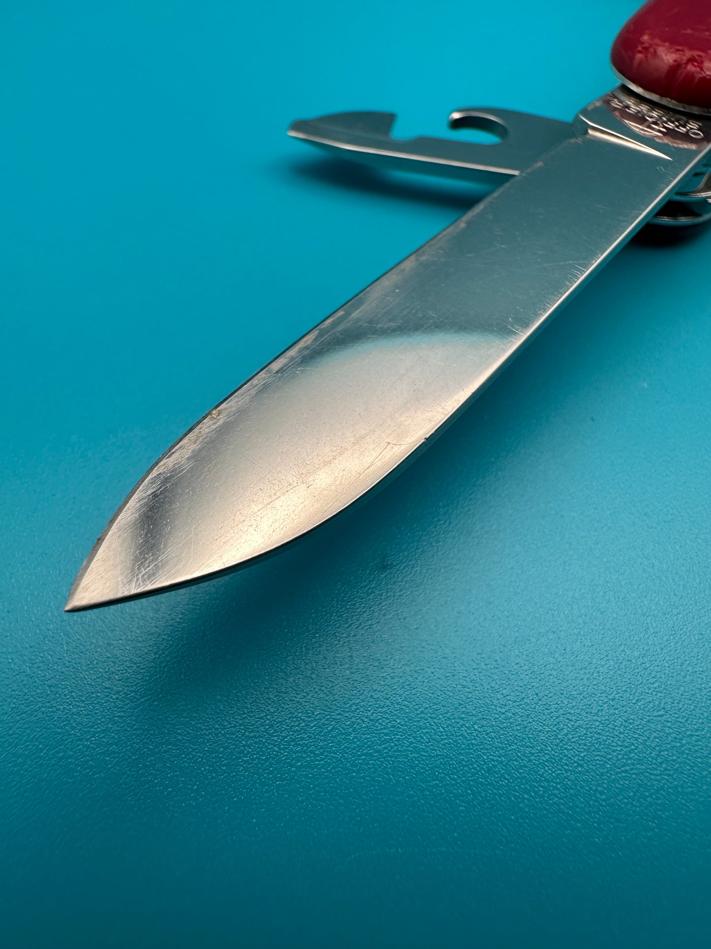 Close-up of the main blade of the Victorinox Huntsman on a blue surface