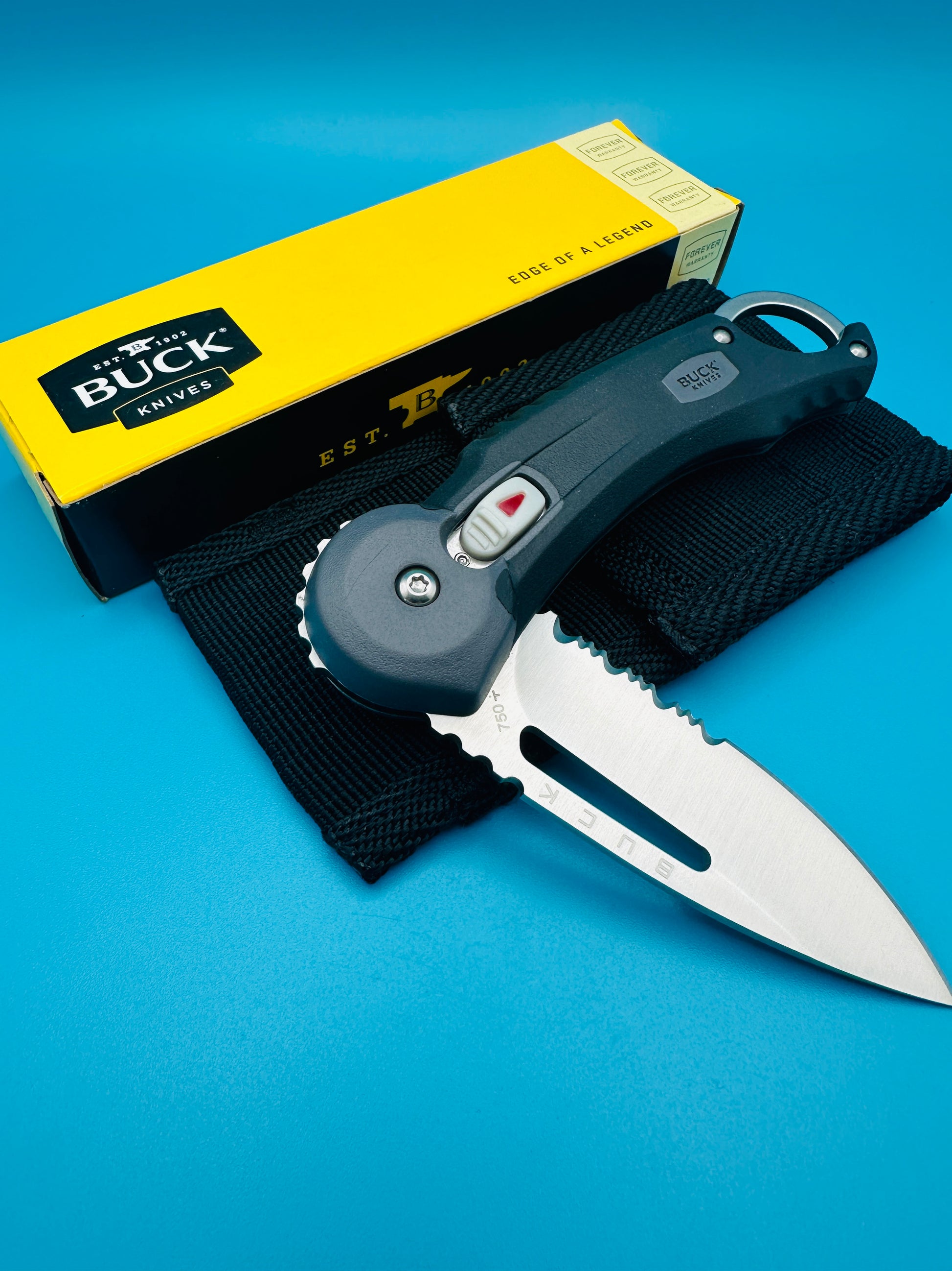 Buck Redpoint black folding knife folded with yellow box, on blue background.