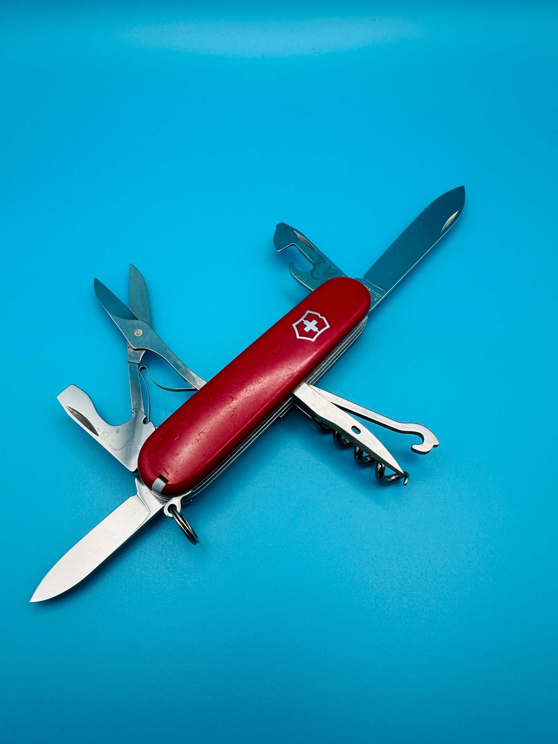 Victorinox Climber multitool with all tools unfolded, displayed diagonally on a light blue surface

