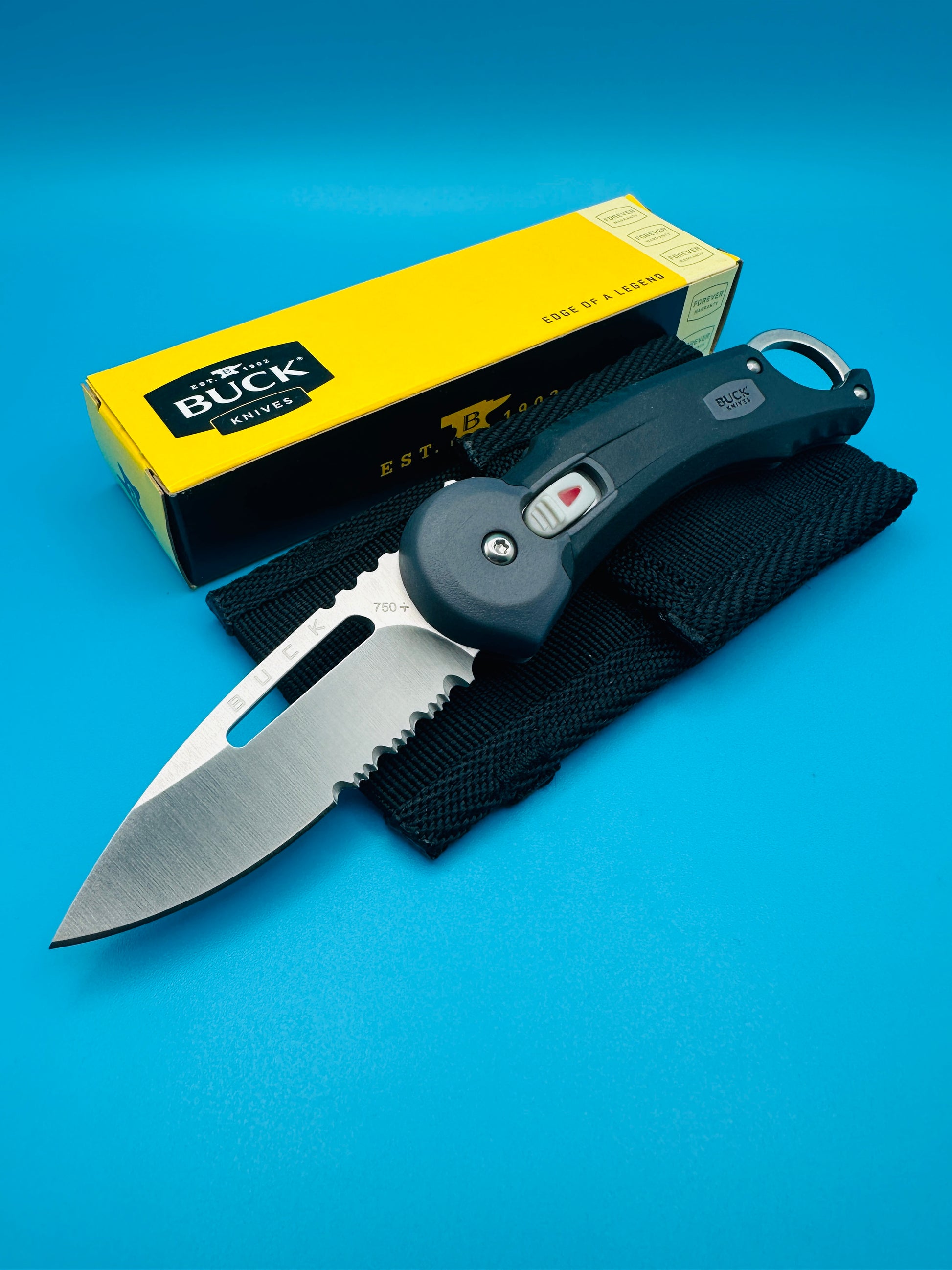Buck Redpoint black folding knife with yellow box, blade partially open, on blue background.