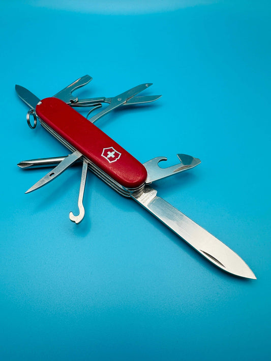 Victorinox Super Tinker Swiss Army knife with tools extended on a blue background, angled view showing large blade and can opener
