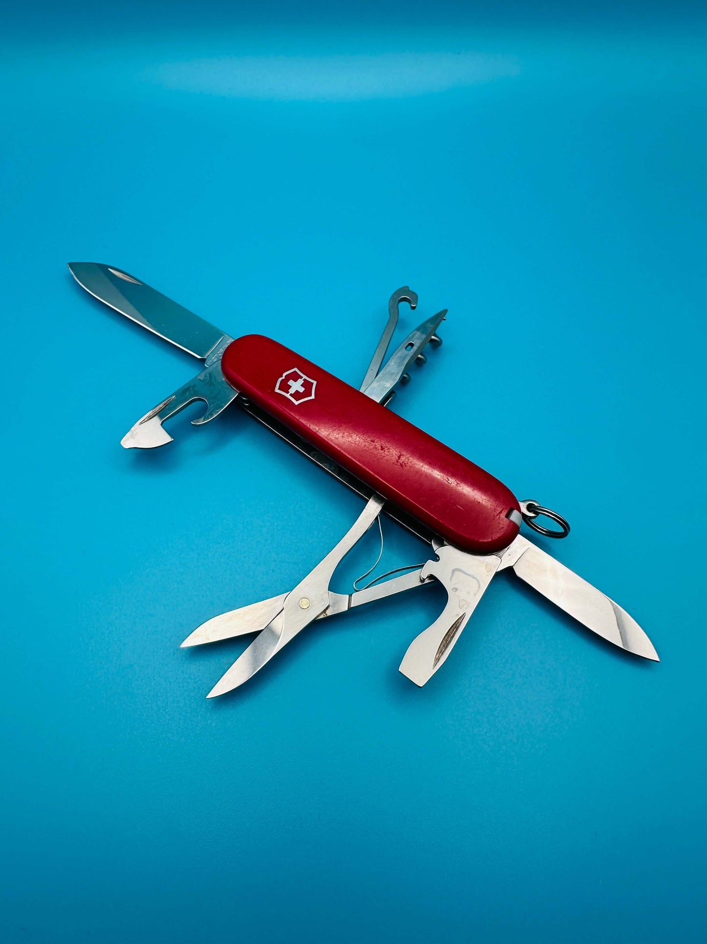 Red Victorinox Climber pocket knife with white cross logo, partially opened with scissors and screwdriver visible